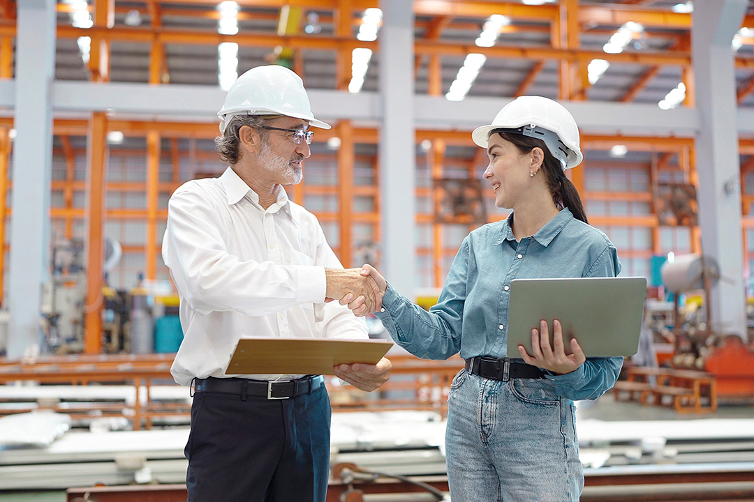 Executives in warehouse reviewing localized operations through end to end supply chain design